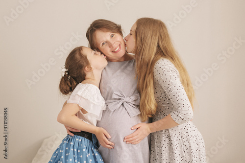Happy kids holding belly of pregnant woman at home cozy environment. © Sergey Khamidulin