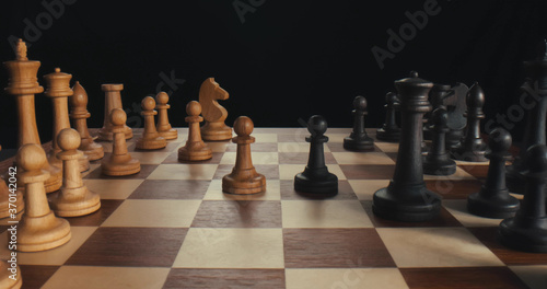 Close up side view of businessmen playing chess making moves with white and black wooden figures