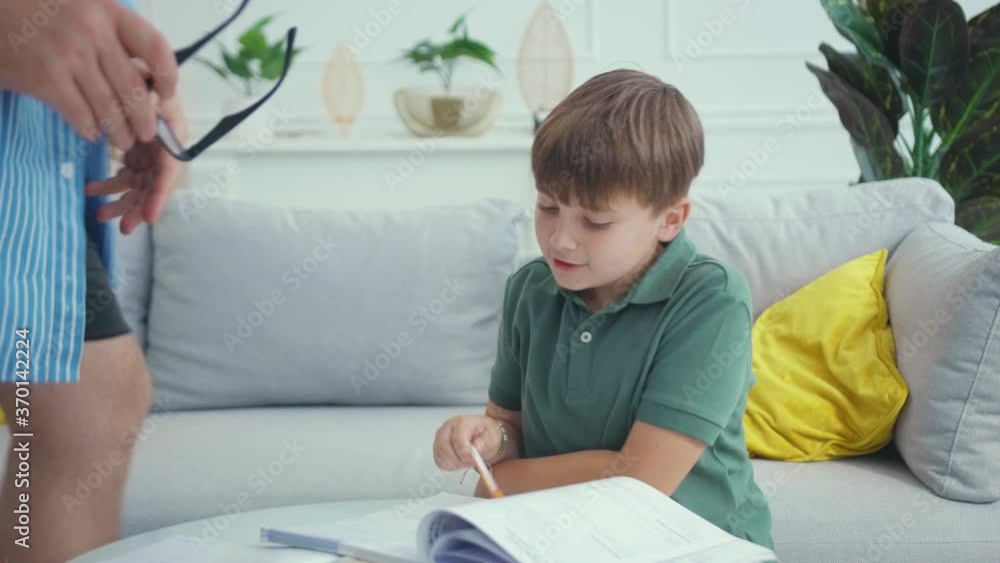 Sad tired child boy offers his father play computer games. Calm serious bearded daddy wearing glasses helping son learning doing homework. Education concept. Sad tired child boy offers his father play computer games. Calm serious bearded daddy wearing glasses helping son learning doing homework. Education concept.
