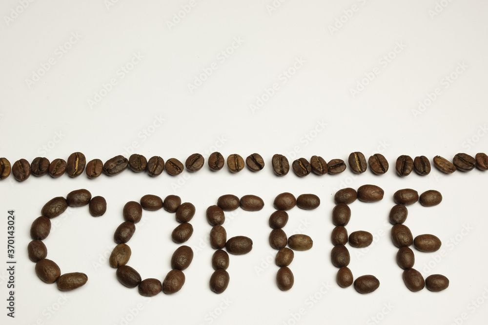 The word COFFEE is laid out on a white background with coffee beans. Above it is a strip of coffee beans The word COFFEE is laid out on a white background with coffee beans. Above it is a strip of coffee beans
