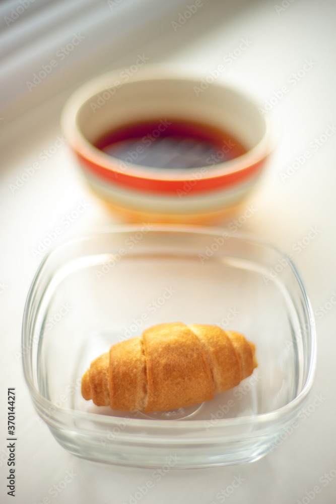 croissant in glass bowl and tea on the windowsill. croissant in glass bowl and tea on the windowsill.