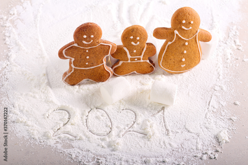Fototapeta premium Gingerbread family biscuits over icing sugar and new year