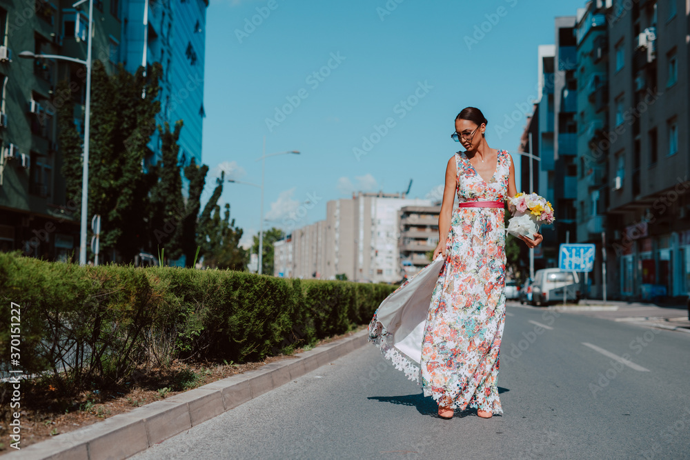 Young beautiful stylish caucasian woman model in summer dress with flower box in her hand on the street Young beautiful stylish caucasian woman model in summer dress with flower box in her hand on the street