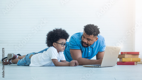 African dad helping Black son in e-learning.  Online learning, teaching safety internet using.