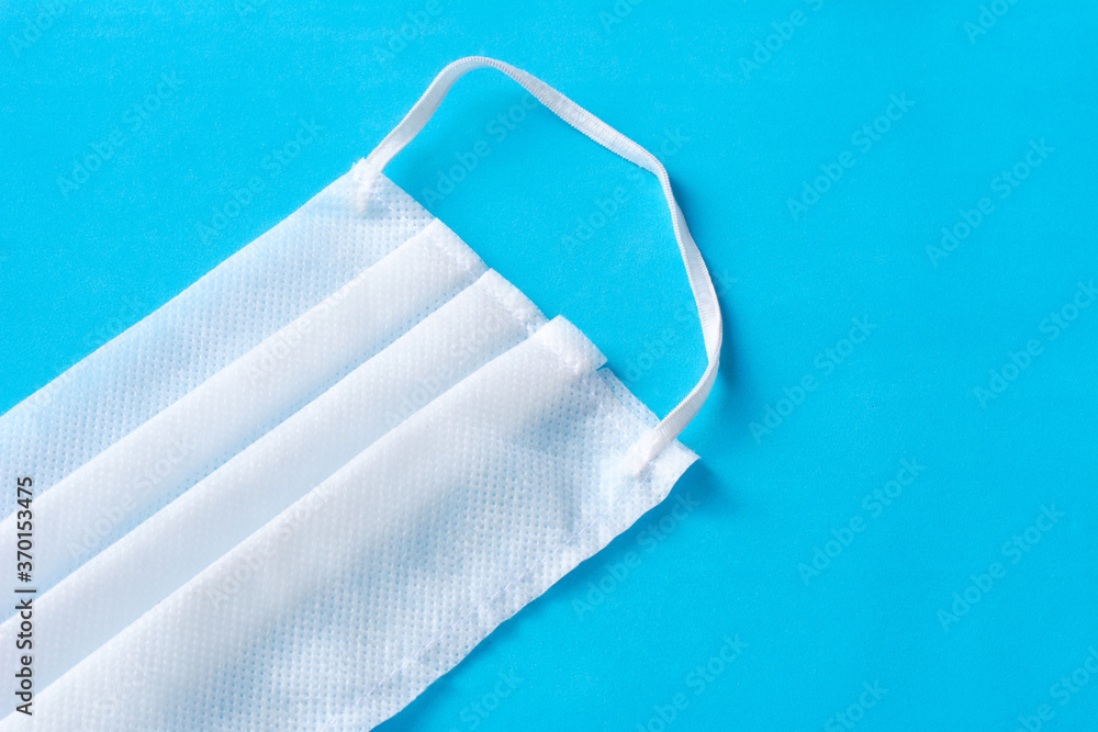 Medical mask or surgical earloop face mask on porous blue background. Healthcare and medical. Coronavirus quarantine, hygiene concept Medical mask or surgical earloop face mask on porous blue background. Healthcare and medical. Coronavirus quarantine, hygiene concept