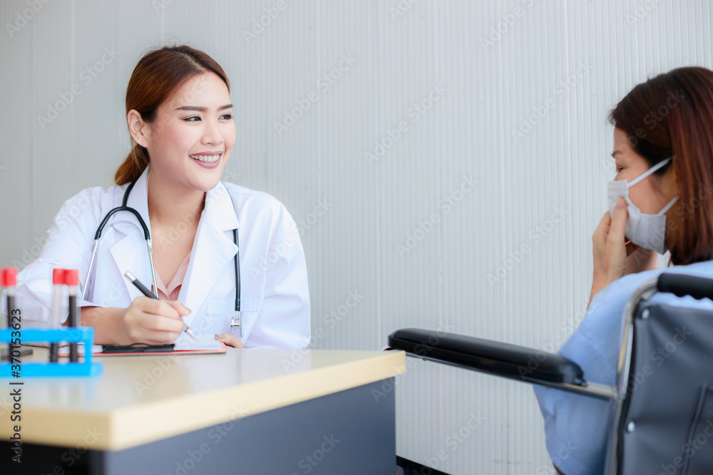 Beautiful young Asian female doctor is recording a medical history on the clipboard and explaining something to the female patient. Medical and health care concepts