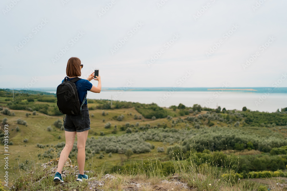 Woman hiker taking photo with smart phone at hill peak. Internal tourism concept. Europe Woman hiker taking photo with smart phone at hill peak. Internal tourism concept. Europe
