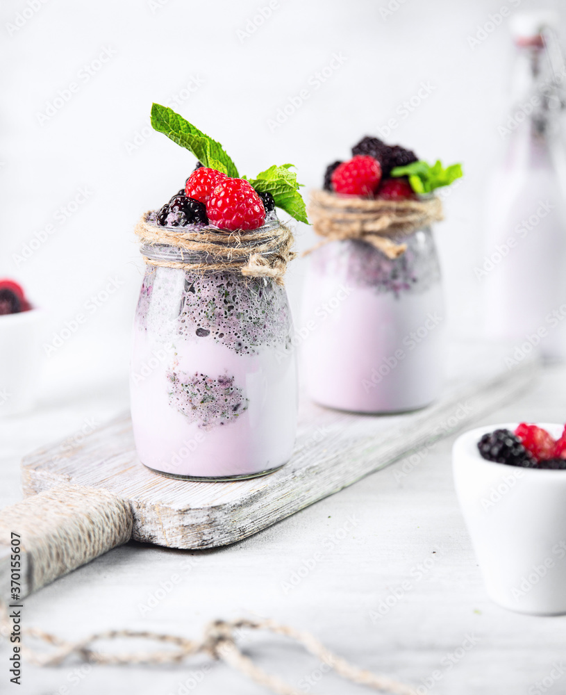 Berry milkshake in glass bottles on white wooden cutboard on white. Berry milkshake in glass bottles on white wooden cutboard on white.