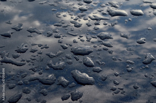 Rain drops on top of the dark car roof.Water drops on car roof after raining   selective focus