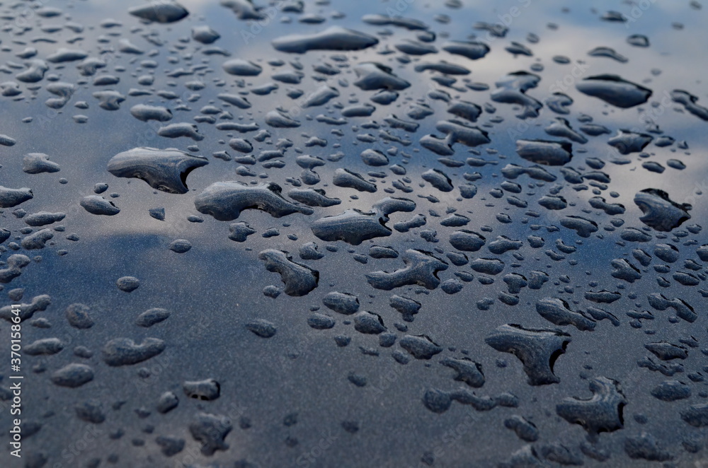 Rain drops on top of the dark car roof.Water drops on car roof after raining , selective focus Rain drops on top of the dark car roof.Water drops on car roof after raining , selective focus
