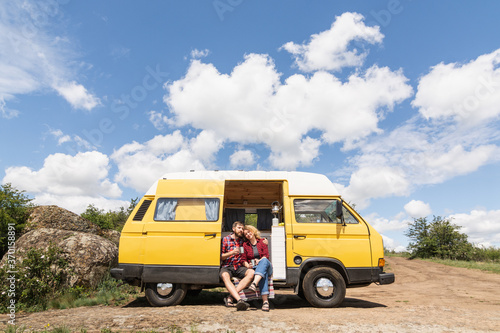 Young couple travelling by yellow campervan though the countryside