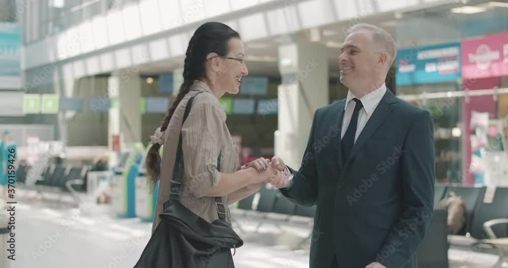 Mid-adult Caucasian man with nameplate meeting cheerful woman in airport. Businessman greeting smiling tourist in waiting area. Business trip, international tourism. Cinema 4k ProRes HQ. Mid-adult Caucasian man with nameplate meeting cheerful woman in airport. Businessman greeting smiling tourist in waiting area. Business trip, international tourism. Cinema 4k ProRes HQ.