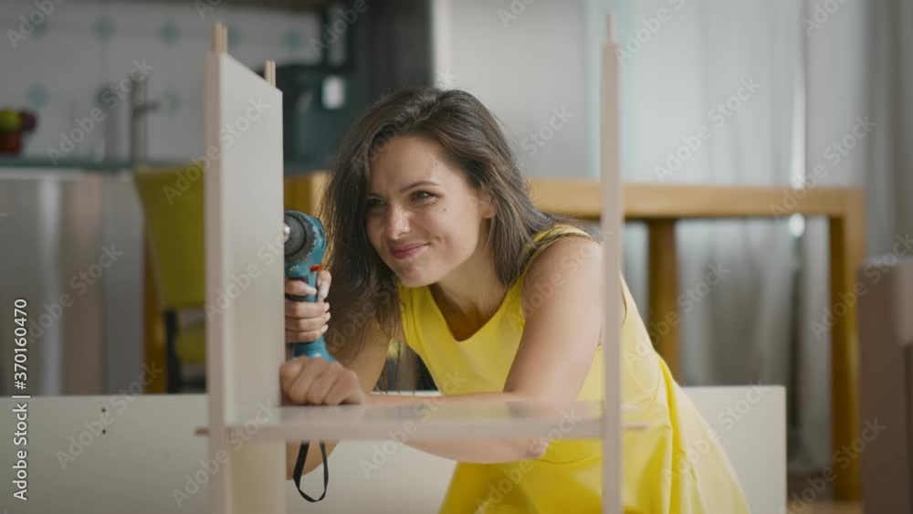 Portrait of beautiful young woman putting together new furniture using screwdriver Portrait of beautiful young woman putting together new furniture using screwdriver