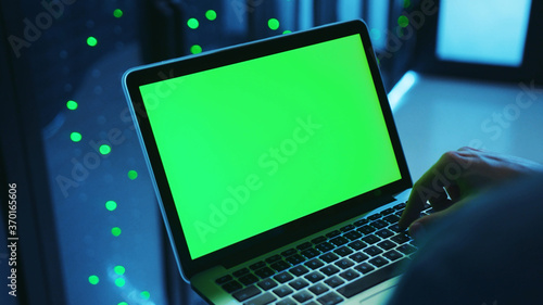 Wallpaper Mural Close-up of IT server expert running a neural network on mock-up laptop green monitor, programming backup code on server cabinet, working in professional data center. Torontodigital.ca