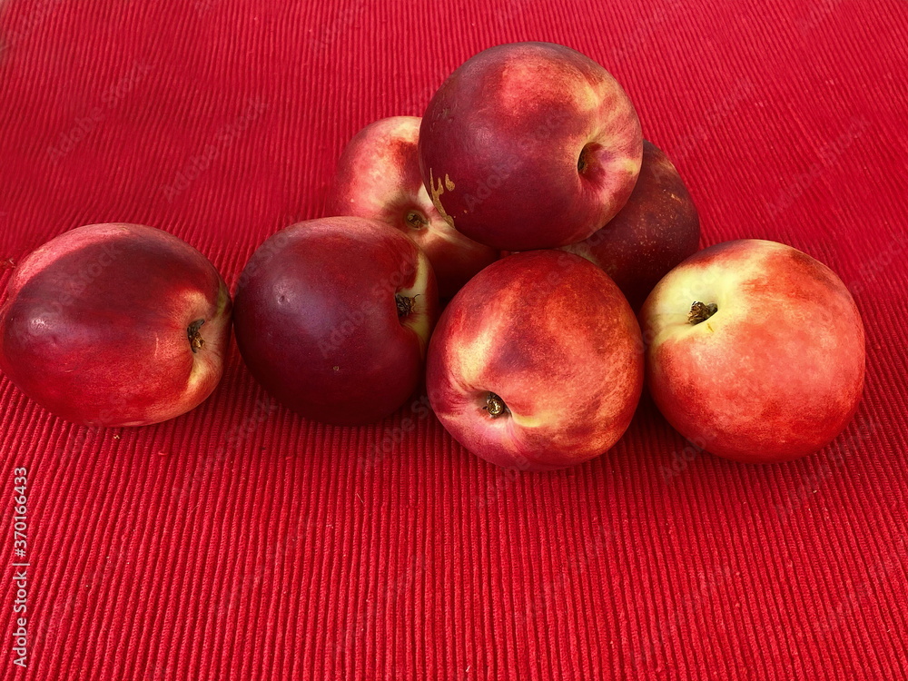 Fresh red nectarine on red cloth napkin on table. Selective focus Fresh red nectarine on red cloth napkin on table. Selective focus