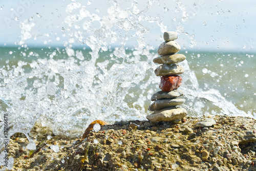 stone tower on rocky beach with wave splashes. soft focus oval pebble one on another make up group.