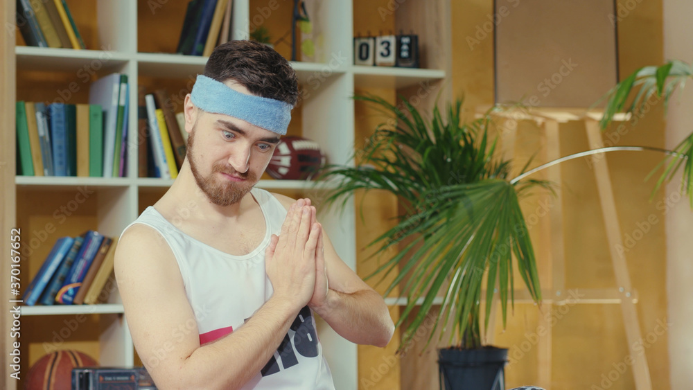 Caucasian funny retro guy pretends to meditate, practicing relaxing yoga asana, secretly taking and eating cookie. Junk food. Silly jerk. Concept of fun, humor, joke and sports. Caucasian funny retro guy pretends to meditate, practicing relaxing yoga asana, secretly taking and eating cookie. Junk food. Silly jerk. Concept of fun, humor, joke and sports.