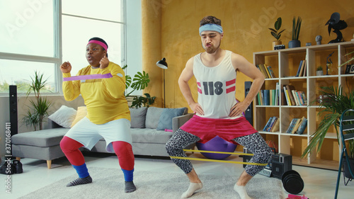 Foto Funny sport freaks wearing retro style clothes and doing wrong stretching exercises with elastic bands