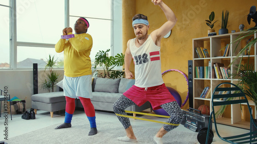 Vászonkép Funny sport freaks wearing retro style clothes and doing wrong stretching exercises with elastic bands