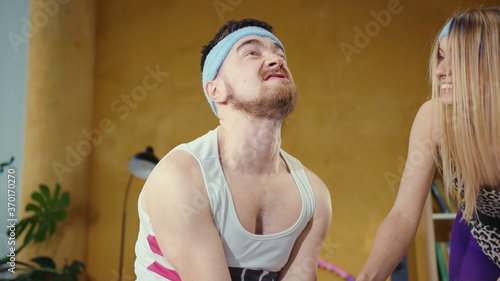 Obraz na plátně Weak strained bearded man lifting up heavy weight dumbbels struggling