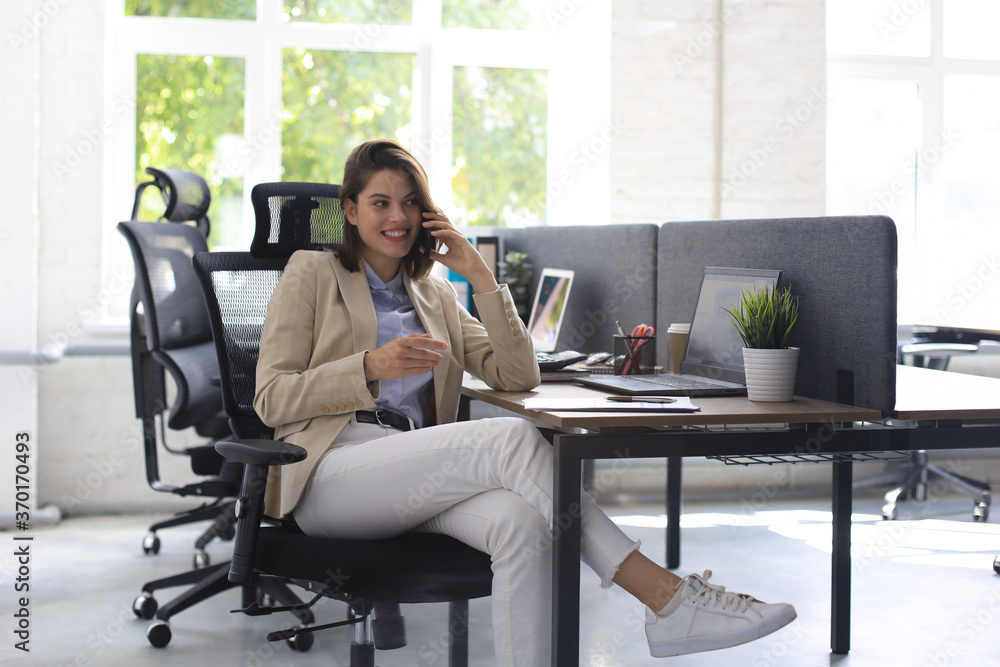 Young smiling business woman using smartphone in office. Young smiling business woman using smartphone in office.
