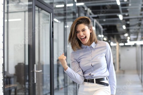 Beautiful businesswoman is keeping arm raised and expressing joyful in office.