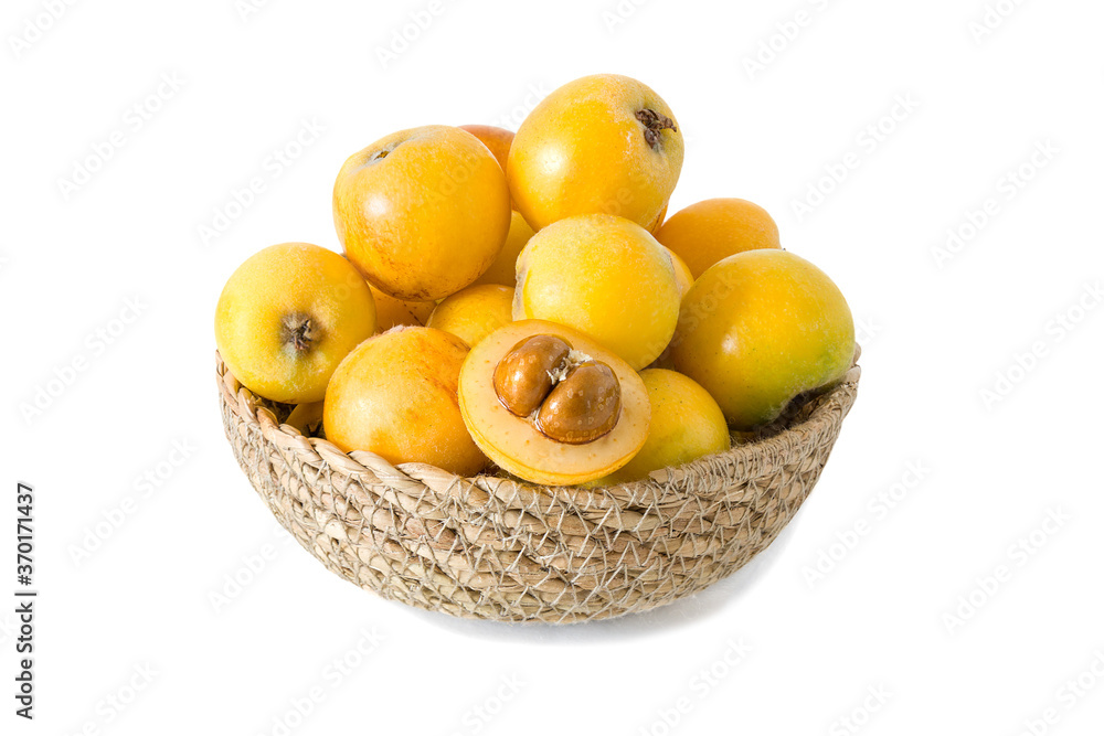 Ripe loquat or Eriobotrya japonica in a wicker basket isolated on white background.