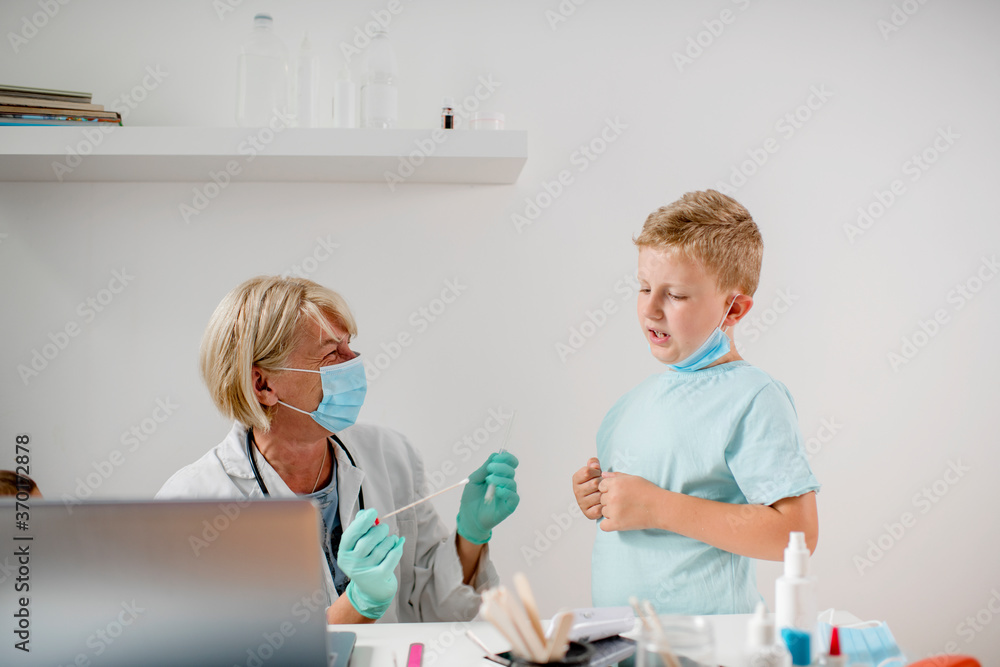 Smiling doctor talking with a boy. They are wearing a protective face mask. Smiling doctor talking with a boy. They are wearing a protective face mask.