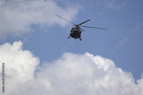 helicopter flies against the background of white clouds
