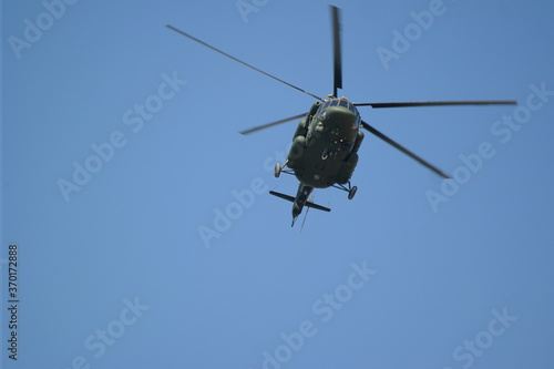 helicopter flies against the blue sky