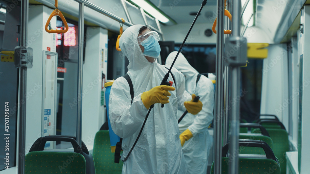 Team of organized cleaners in protective suits disinfecting empty tram on end of day. Professional decontamination. Public transport cleaning. Sanitary measures. Team of organized cleaners in protective suits disinfecting empty tram on end of day. Professional decontamination. Public transport cleaning. Sanitary measures.