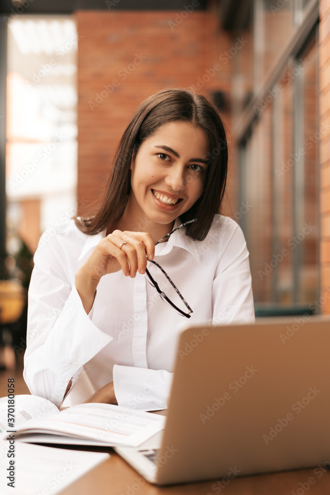 Concentrated at work. Young beautiful woman using her laptop while sitting. Beautiful clever cute charming attractive elegant female owner has online meeting indoors Concentrated at work. Young beautiful woman using her laptop while sitting. Beautiful clever cute charming attractive elegant female owner has online meeting indoors