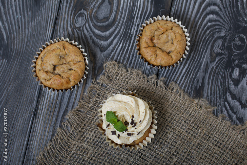 Banana cupcake. With butter cream and banana jam. Decorated with mint leaves and chocolate sprinkles. Next to them are cupcakes without cream Banana cupcake. With butter cream and banana jam. Decorated with mint leaves and chocolate sprinkles. Next to them are cupcakes without cream