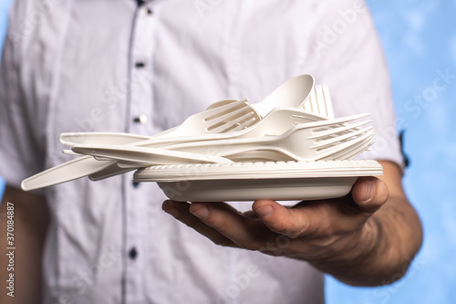 disposable biodegradable cornstarch forks, spoons and plates in male hands. close-up. eco friendly.