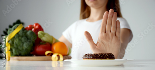 Hands of woman refusing from dessert in favor of vegetables. Balanced diet  healthy nutrition  clean eating  weight loss or detox concept. Banner.