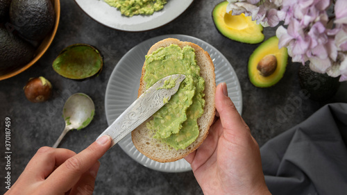 Avocado toast. Woman's hands spreading avocado pasta on bread slice. Healthy food concept. photo