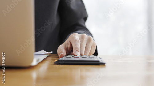 Hand of a business woman is operating Calculator