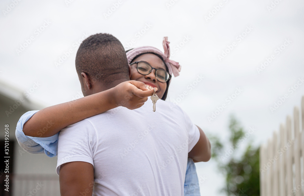 Cheerful african american woman holding home keys while hugging boyfriend in their new house, Happiness family concepts Cheerful african american woman holding home keys while hugging boyfriend in their new house, Happiness family concepts