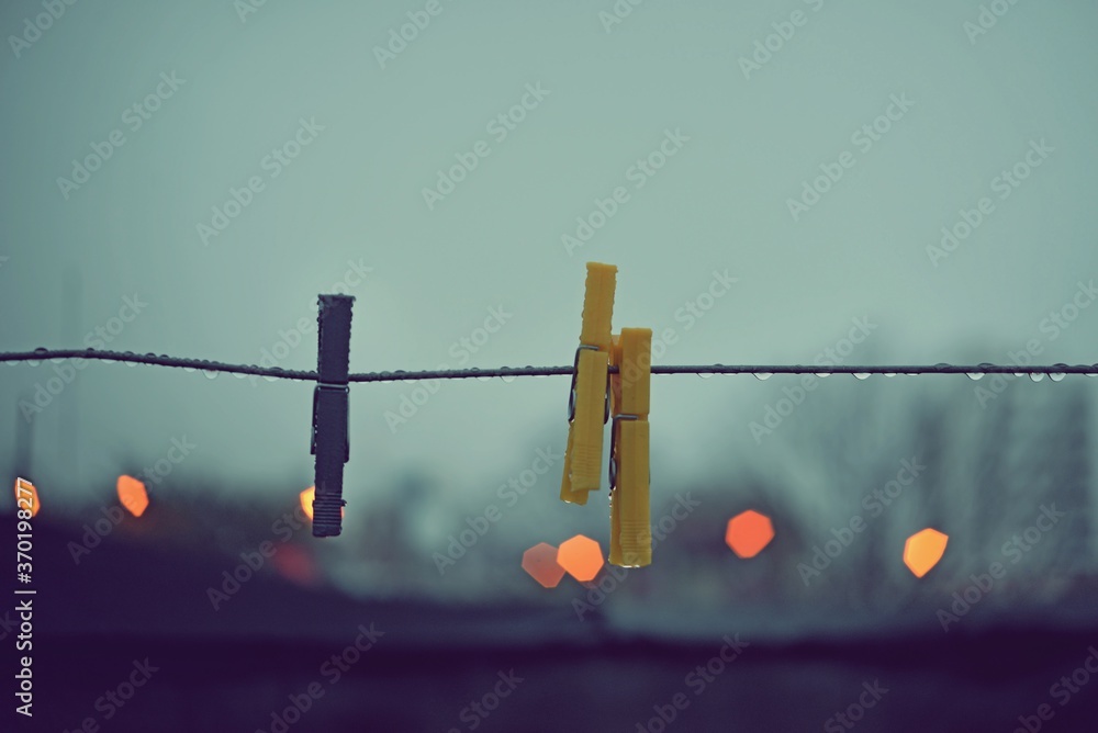 Clothespins on wire with raindrops at sunrise with bokeh of lights in the background Clothespins on wire with raindrops at sunrise with bokeh of lights in the background