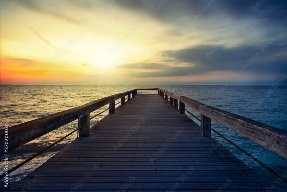 Fototapeta premium Holzsteg im Meer bei Sonnenuntergang