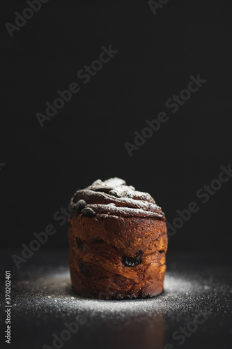 Easter cake kraffin sprinkled with icing sugar on a black background. Holiday baking. Easter traditions. photo