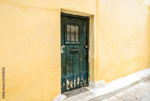 Old door of residential building in Plaka district, Athens, Greece. Traditional house with yellow wall and grunge door on vintage street