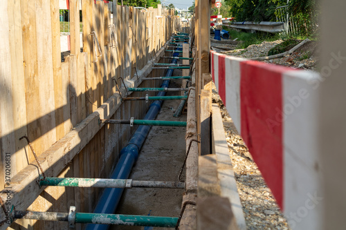 Repair of roads and underground utilities. Big trench on the road with a pipe, the process of repair, or replacing water pipes in a city.
