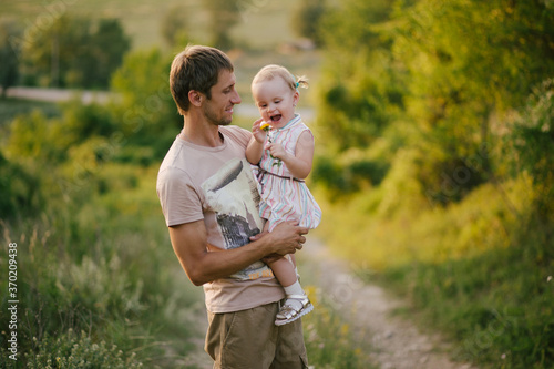 Happy fater and his little daughter walking in a forest at sunset. photo