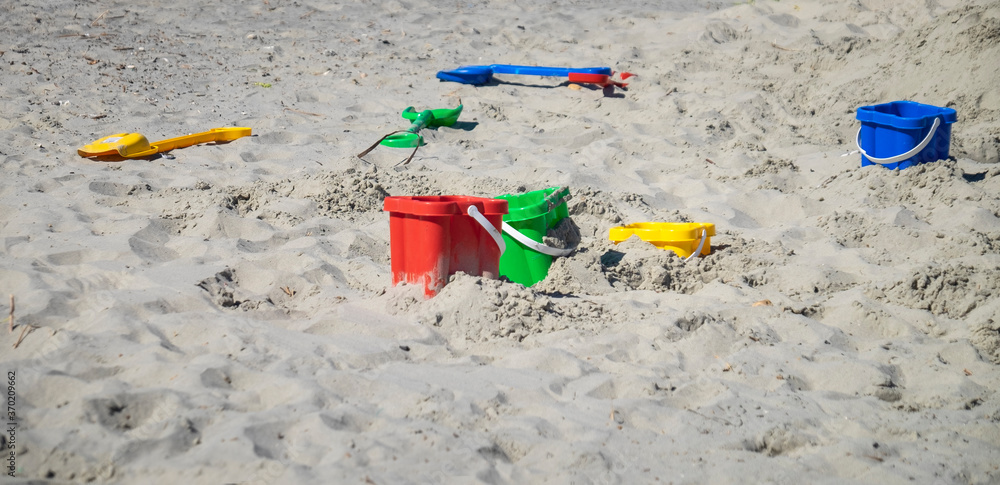 Colourful buckets and spades left laying on a sandy beach. Colourful buckets and spades left laying on a sandy beach.