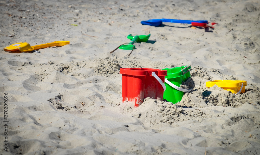 Colourful buckets and spades left laying on a sandy beach. Colourful buckets and spades left laying on a sandy beach.