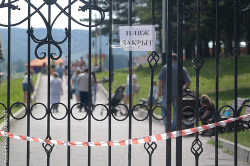 people walk on the closed beach because of quarantine. inscription on the gate in Russian language - the beach is closed
