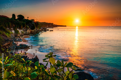 Tropical Beach with rocky mountains and clear water of Indian ocean at sunset. Bali, Indonesia
