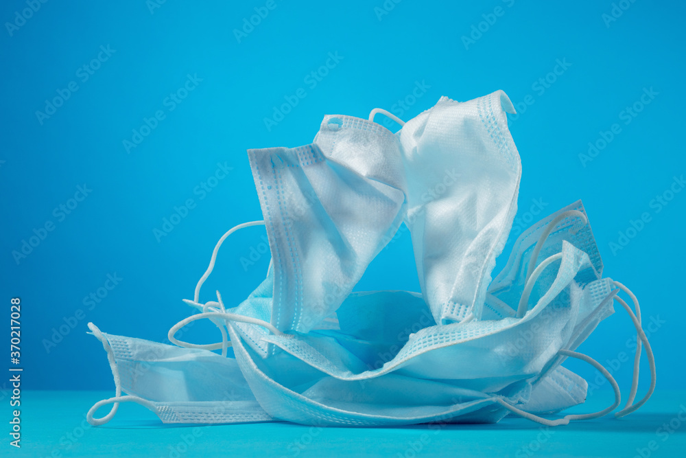 Used medical masks on a blue background. The problem of ecology and disposal of medical waste. Protection against coronavirus, covid-19 Used medical masks on a blue background. The problem of ecology and disposal of medical waste. Protection against coronavirus, covid-19