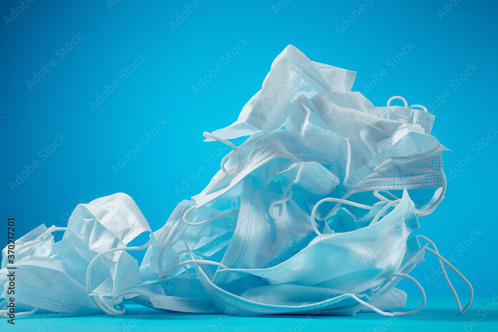 Used gloves, medical masks on a blue background. The problem of ecology and disposal of medical waste. Protection against coronavirus, covid-19 Used gloves, medical masks on a blue background. The problem of ecology and disposal of medical waste. Protection against coronavirus, covid-19
